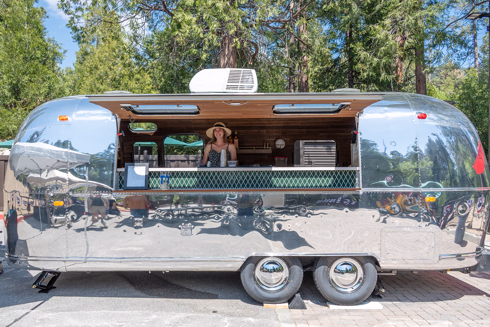 A bartender at the window of Idyllwild Brewpub's polished Airstream beer trailer