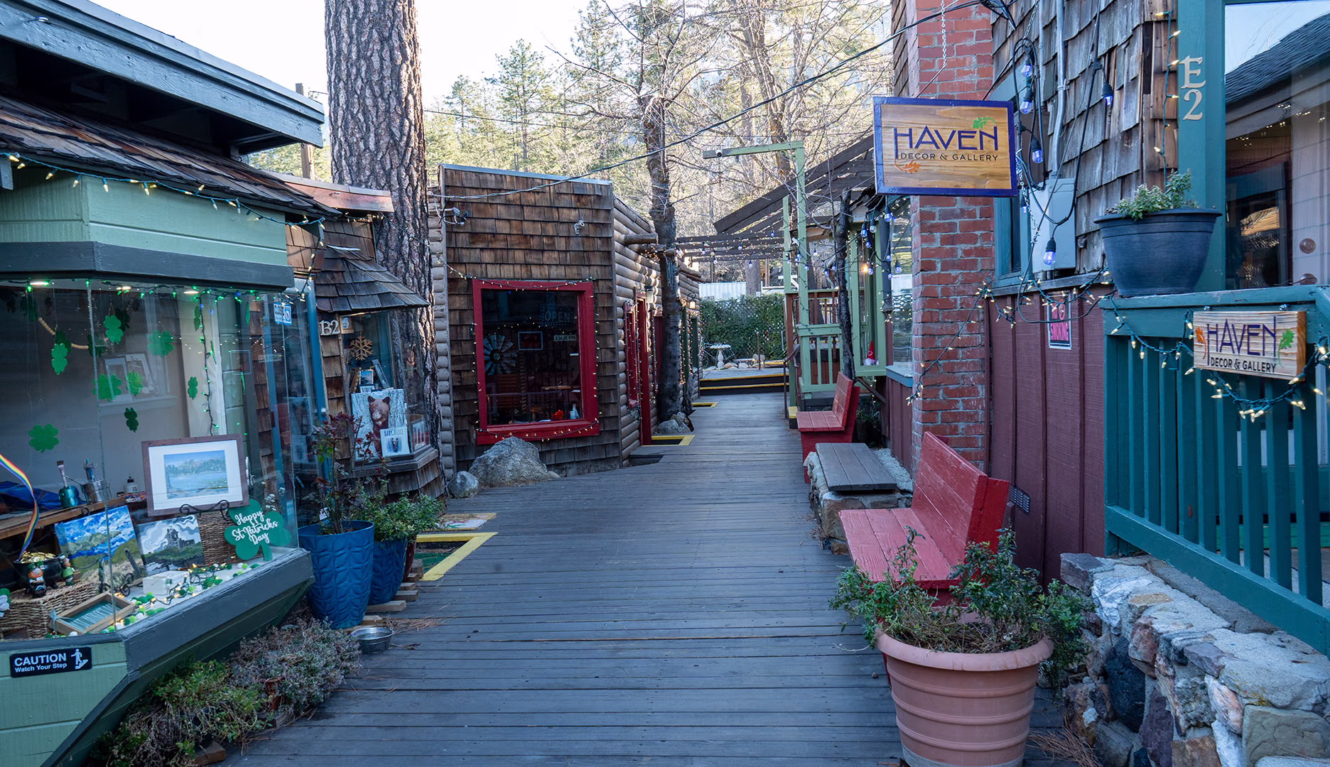 A wooden walkway between log-sided shops strung with lights in Idyllwild's village