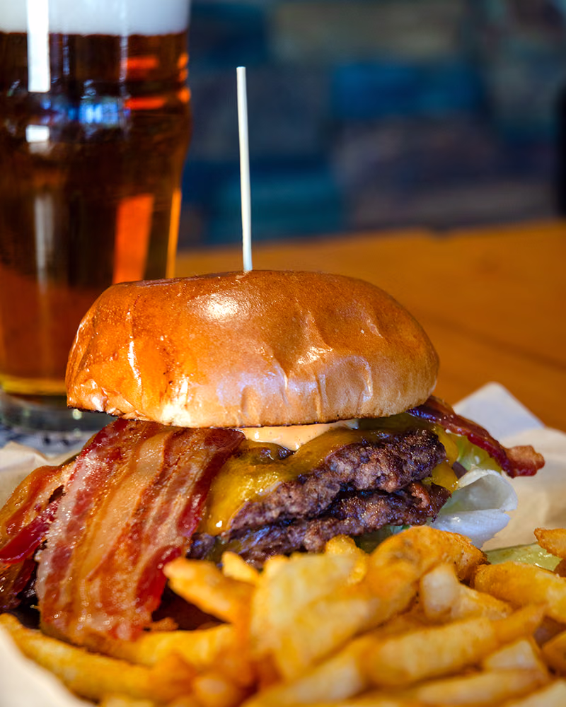 A double bacon cheeseburger with fries and a pint of beer