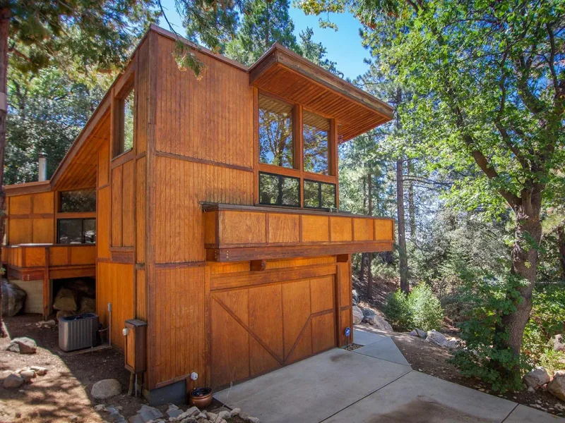 Copper Mine, a wood-sided cabin with a garage and an upper deck among the trees