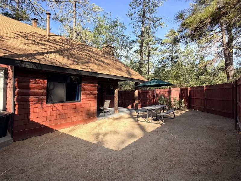 Enchanted Forest, a red cabin with a fenced patio under the pines
