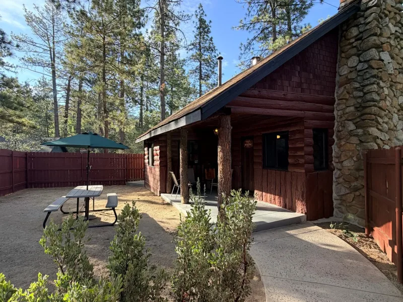 Kid Galahad Lodge, a log cabin with a covered porch and a fenced patio under the pines